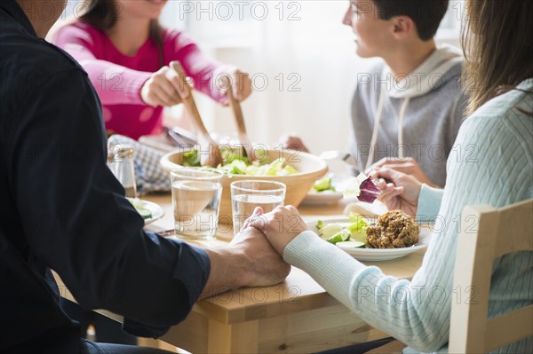 Caucasian parents holding hands at table