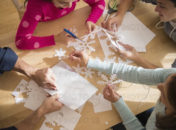 Caucasian family cutting out paper snowflakes