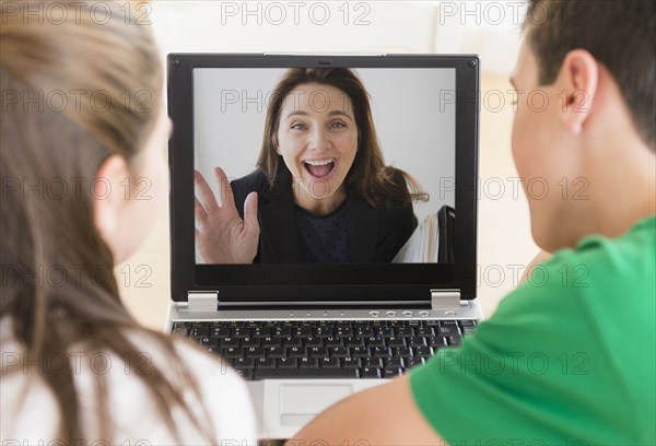 Caucasian children video conferencing with mother on laptop