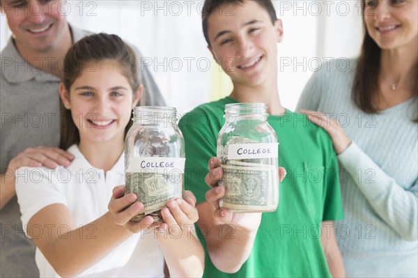 Proud Caucasian parents watching children with college savings jars