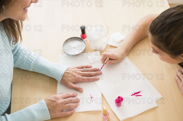 Caucasian girl giving mother a manicure