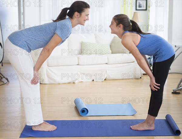 Caucasian mother and daughter practicing yoga in living room