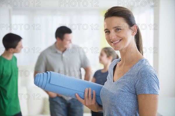 Portrait of smiling woman holding yoga mat