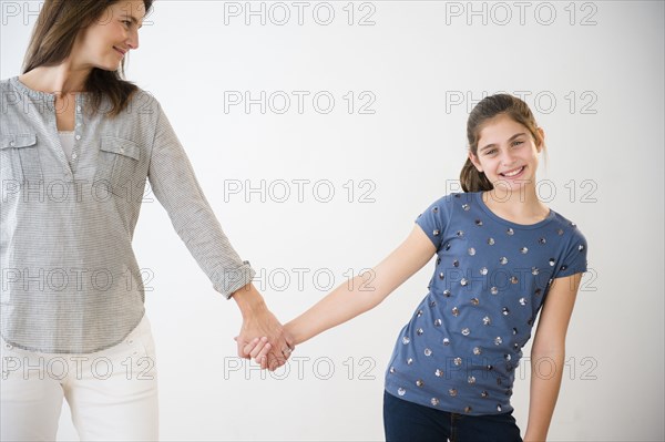 Portrait of smiling Caucasian daughter holding hands with mother