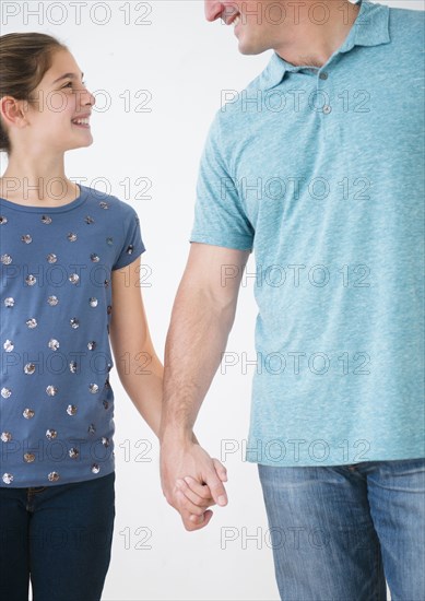 Smiling Caucasian father and daughter holding hands