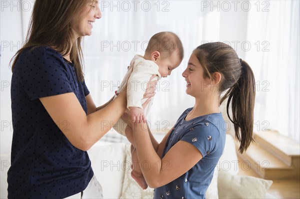 Caucasian mother handing baby girl to daughter