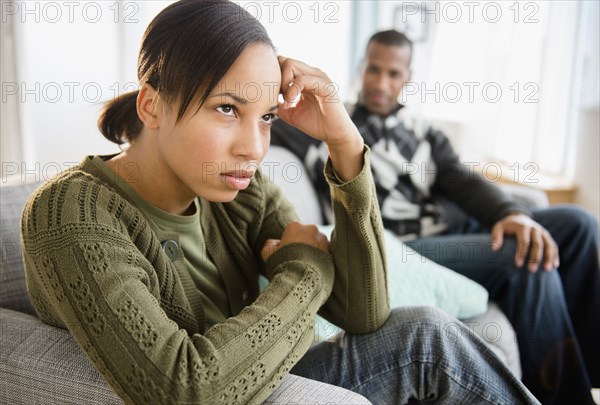 Boyfriend watching frustrated girlfriend on sofa