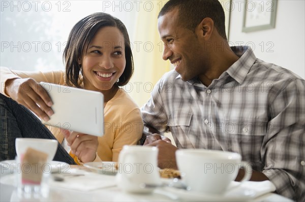Happy couple drinking coffee and using digital tablet
