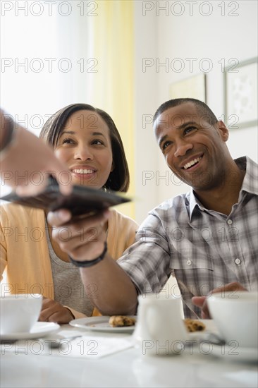 Couple receiving bill from waitress in restaurant