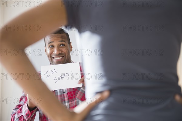 Man showing 'I'm Sorry' sign to angry girlfriend