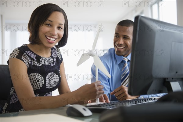 Portrait of smiling business people with wind turbine at computer