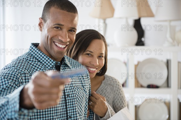 Portrait of happy couple paying with credit card in store