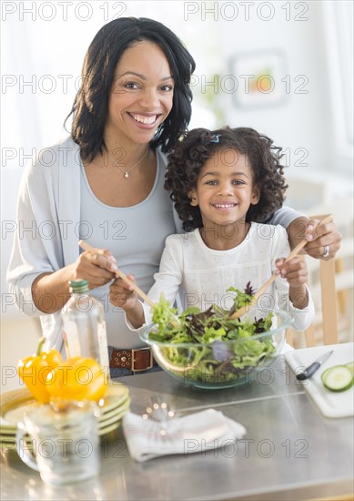 African American mother and daughter tossing salad