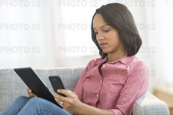 African American woman using cell phone and digital tablet