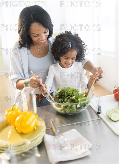 African American mother and daughter tossing salad