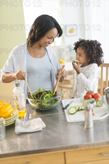 African American mother and daughter tossing salad