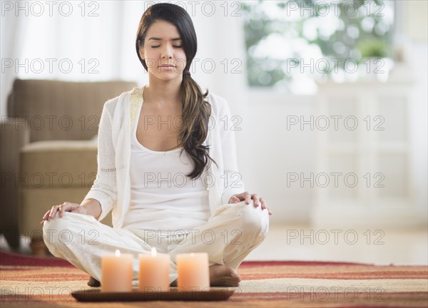 Serene Hispanic woman meditating near lit candles