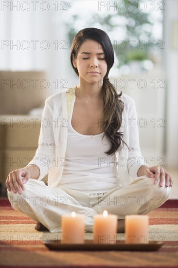 Serene Hispanic woman meditating near lit candles