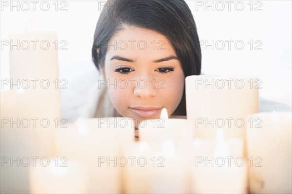 Hispanic woman looking down at lit candles