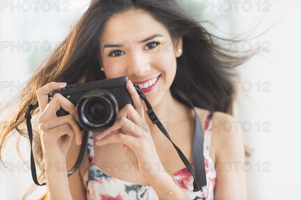 Portrait of smiling Hispanic woman holding digital camera