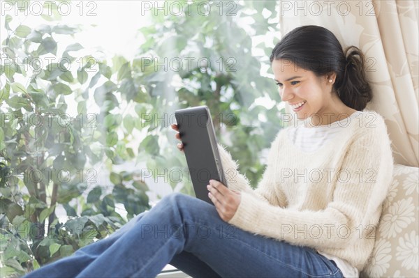 Hispanic woman using digital tablet at window seat