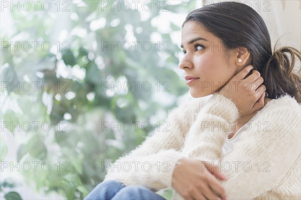 Pensive Hispanic woman looking out window