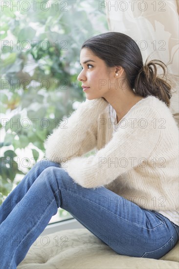 Pensive Hispanic woman looking out window