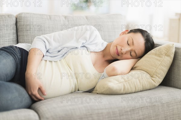 Pregnant Japanese woman napping on sofa