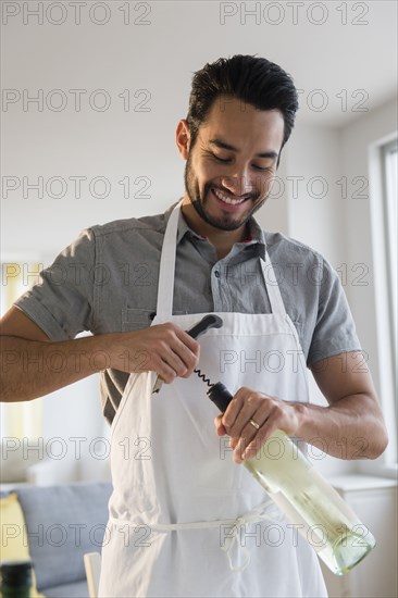 Mixed race man opening wine bottle