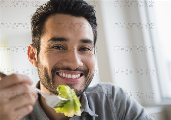 Mixed race man eating salad