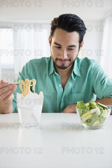 Mixed race man choosing take out or salad