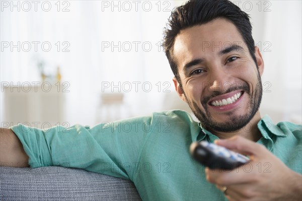 Mixed race man watching TV on sofa