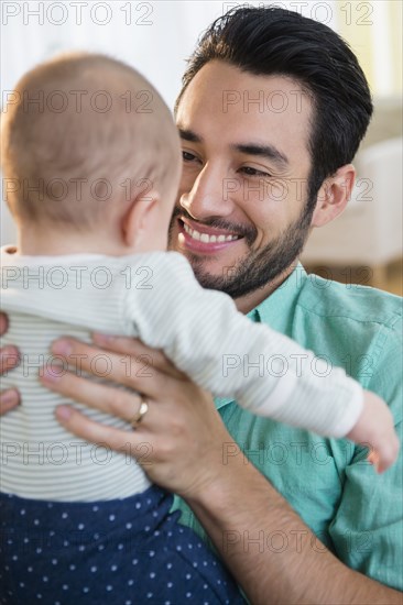 Father holding baby on sofa