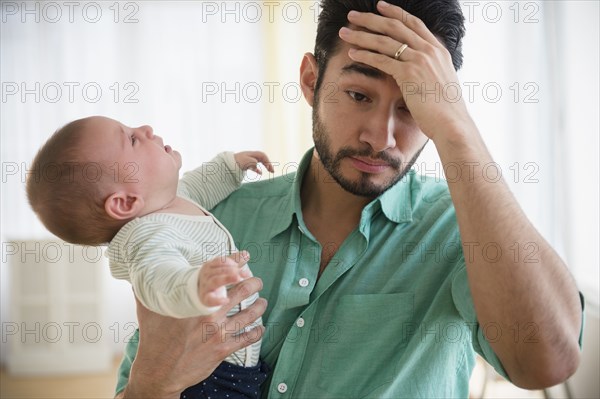 Frustrated father holding crying baby