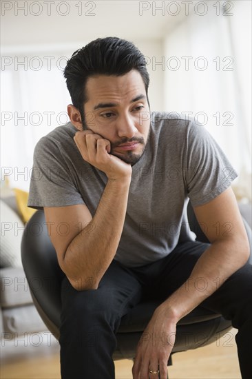 Mixed race man resting chin in hand