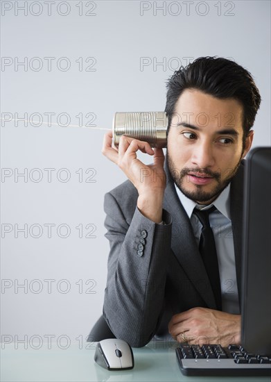 Mixed race businessman using tin can telephone
