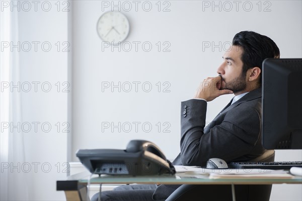 Mixed race businessman thinking in office