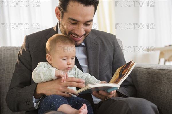 Father reading to baby on sofa