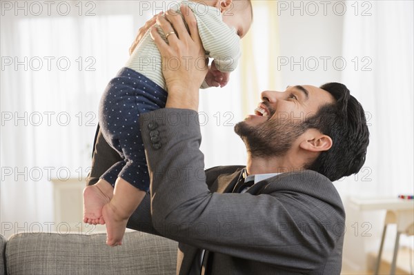Father playing with baby on sofa
