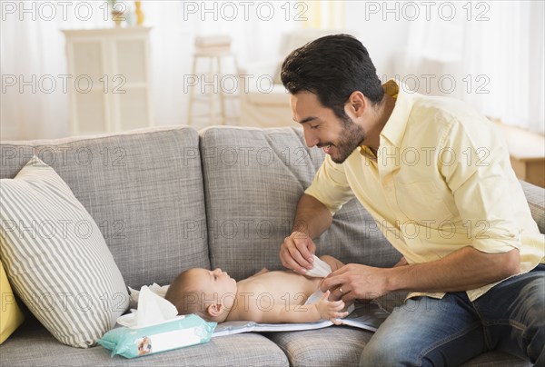 Father changing baby's diaper on sofa