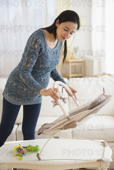 Pregnant Caucasian woman setting up baby chair