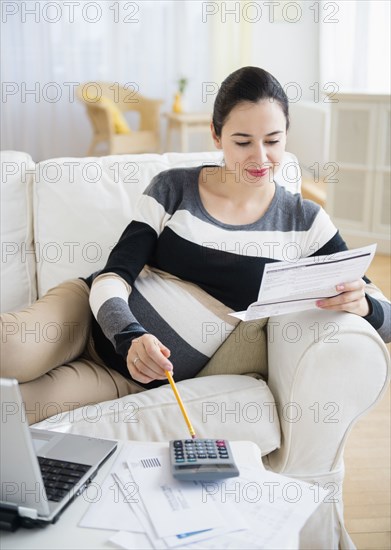 Pregnant Caucasian woman paying bills