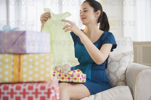 Pregnant Caucasian woman opening baby shower gifts