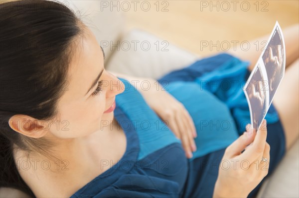 Pregnant Caucasian woman examining ultrasounds