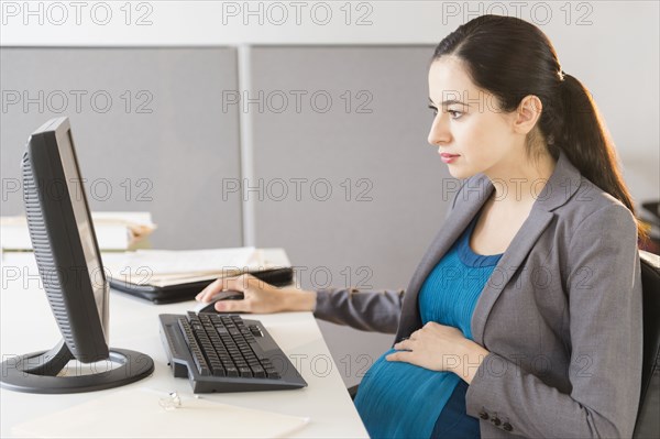 Pregnant Caucasian businesswoman working in office