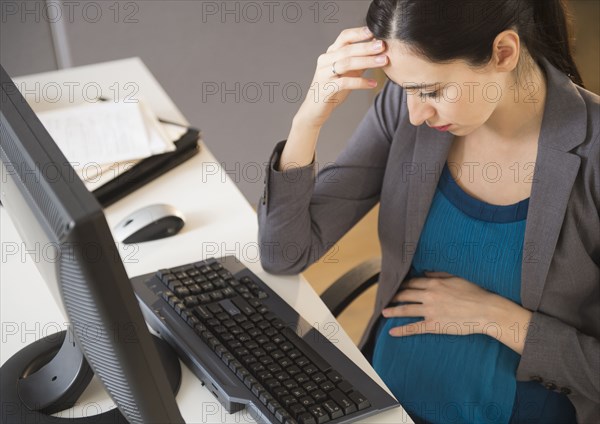 Pregnant Caucasian businesswoman working in office