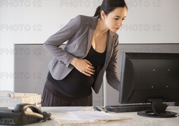 Pregnant Caucasian businesswoman working in office