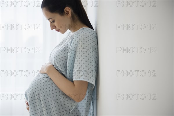 Pregnant Caucasian woman holding her belly in hospital