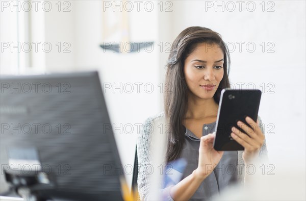 Hispanic businesswoman using digital tablet in office