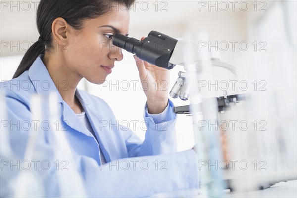 Hispanic scientist using microscope in laboratory